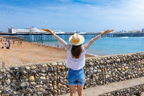 Foto Rear view of a happy woman looking at the beach and famous beach and Pier of Bri