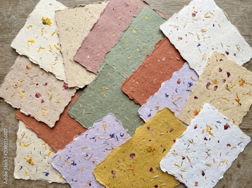 Artistic arrangement of colorful handmade paper sheets with flower petals on a surface