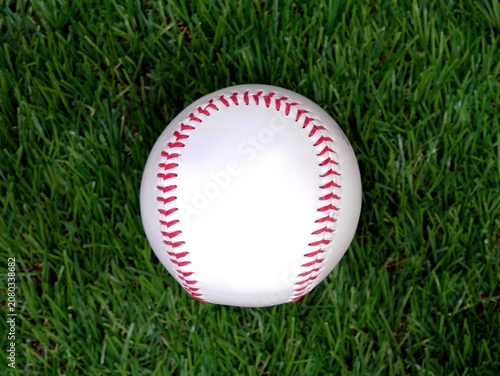 A white baseball with red stitching on the grass