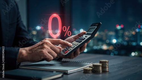 Businessman using a calculator with zero percent interest rate hologram at night