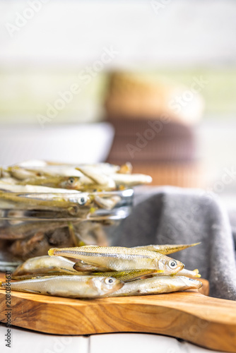фотографія Fresh Whitebait Small Fish Stack on Wooden Board With Glass Bowl of Seafood