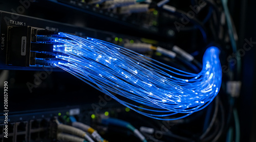 Glowing blue cables connected to server in dark data center room