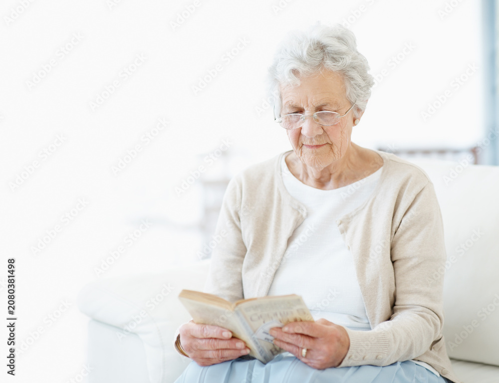 Obraz premium Calm, book or old woman on couch with reading, fantasy novel or insight in literature hobby. Space, glasses or senior person in house with fairytale, peaceful moment or fiction story in retirement.