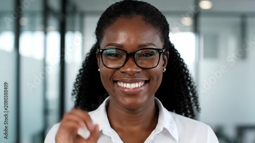 Smiling young African American businesswoman with glasses looking at camera in office.
