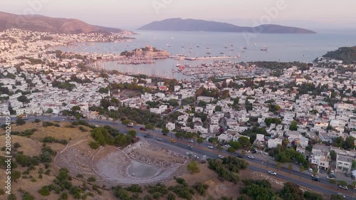 Cinematic aerial drone reveal over historic Bodrum showing ancient Halikarnassos amphitheater medieval Castle of Saint Peter marina with Turkish gulets and Aegean Sea at golden hour Mugla Turkey