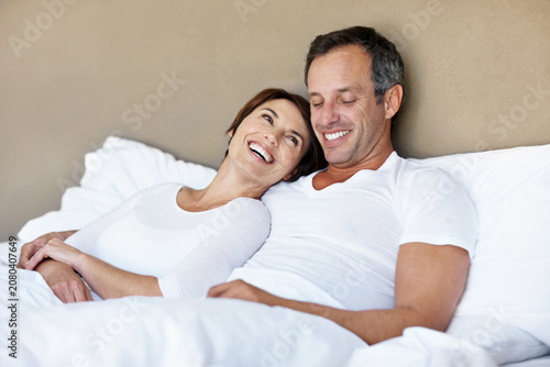 Photography Love, care and laughing with couple in bedroom in home for wake up, connection and romantic partner