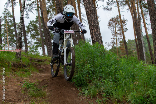 Athlete racer riding downhill on forest trail