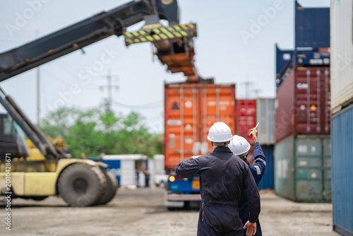 Fotografie Industrial logistics team observing container handling equipment during freight loading process