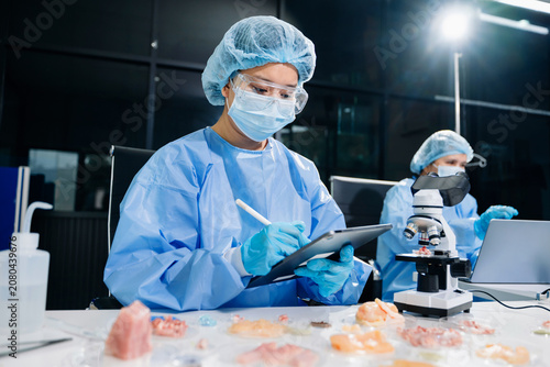 Food scientists examining meat samples in a laboratory. Food safety, quality control, microbiology, biotechnology, laboratory research and professional teamwork.