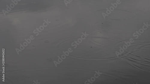 Big puddle of water after nightly thunderstorm with raindrops an car passing with splashing water on a rainy summer morning. Slow motion video shot July 1st, 2026, Zurich Rümlang, Switzerland.