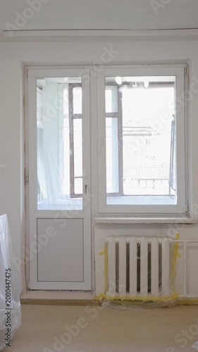 Old wooden window and balcony door being replaced with new modern white pvc frames during renovation