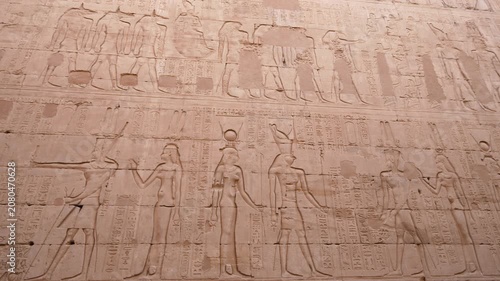 Detailed stone wall carvings featuring ancient Egyptian gods and hieroglyphics at the historic Temple of Edfu in Egypt.
