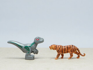 Mini toy of action figure at table with blur background. Miniature photography concept design. Minifigure of Dinosaurs and Tiger character. Animal at wildlife.