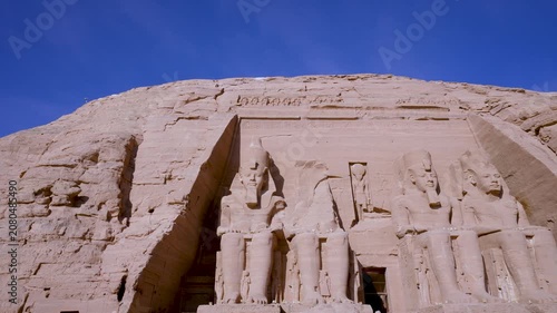 A low angle view of the massive stone facade of the Great Temple of Abu Simbel in Aswan, Egypt, featuring colossal statues of Ramses II.