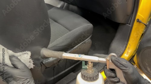 The process of professional detailing dry cleaning of the interior of the car using chemistry and tornado air gun. The detailing master cleans car interior with a hot steam cleaner, brush, microfiber.