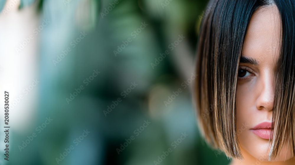 Obraz premium Close up portrait of young woman with curly hair in natural light outdoor setting