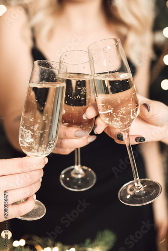 Fotografie Close up of women hands clinking champagne glasses during a festive holiday party