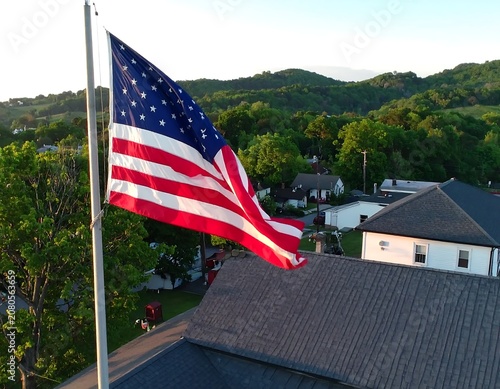 American Flag Waving High Above a Residential Neighborhood at Sunset.
