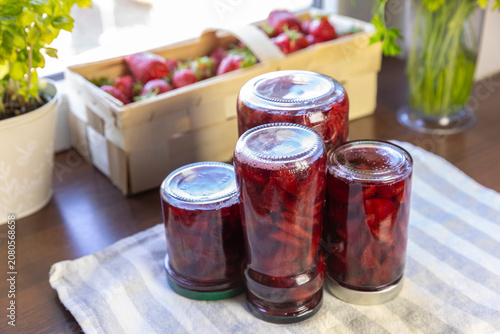 Fotografie homemade strawberry jam in glass jars on the kitchen table, preserving seasonal