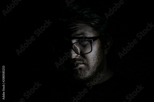 фотографія Darkness frames a man's face, half-lit by subtle light