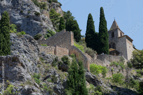 Notre-Dame-de-Beauvoir chapel on a rocky cliff with ancient stone walls and cypress trees, Moustiers-Sainte-Marie, Provence, France.