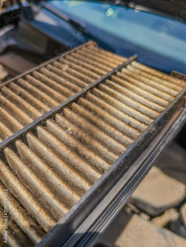 Фотография Dirty engine intake filter seen inside vehicle hood with signs of wear and dust