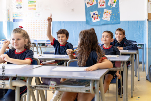 Young students smiling, sitting at desks, and participating in a classroom lesson, reflecting active learning and engagement