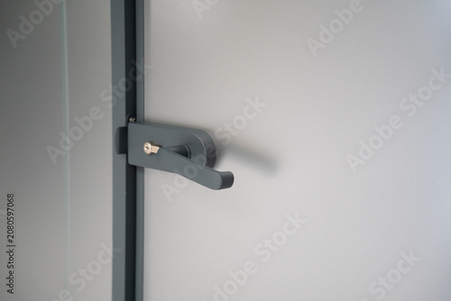 Modern door handle with key lock on a minimalist interior office door. Contemporary architectural hardware for office security and commercial interior design