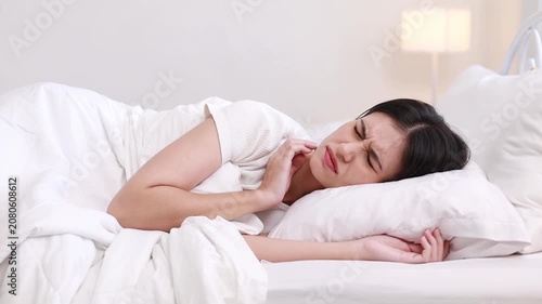 The unhappy young woman lay in bed, waking up in the morning with severe neck pain, aching from a restless sleep.
