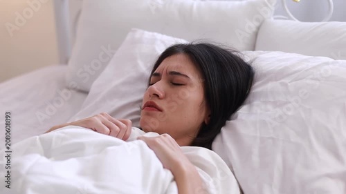 A young woman experiencing nightmares while sleeping in her bedroom at home in the morning could be caused by headaches, migraines, insomnia, sleep apnea, or stress.