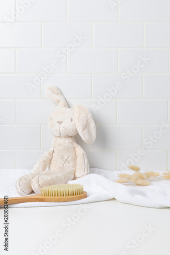 Baby product mockup background with cute plush bunny toy on white bathroom counter. Empty space for newborn skincare, shampoo, or baby cosmetic display.