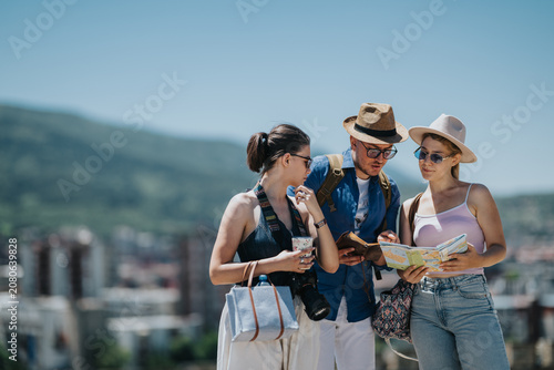 Foto Three tourists consult a paper map while standing outdoors in a city