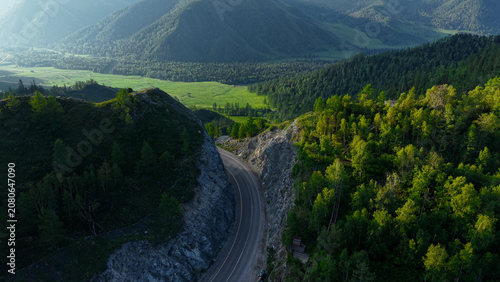Foto A cinematic drone revealing shot flying over a rocky mountain cleft to uncover a scenic asphalt road and a lush green valley at Chike-Taman Pass in Altai
