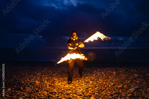 Fire performer with burning torches at night