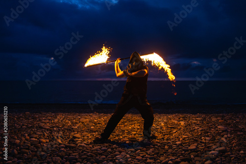 Fire performer with burning torches at night