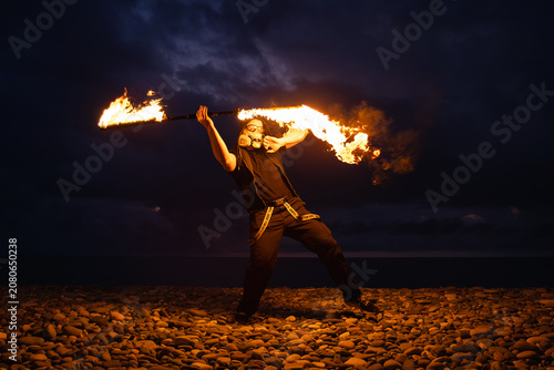 Fire performer with burning torches at night