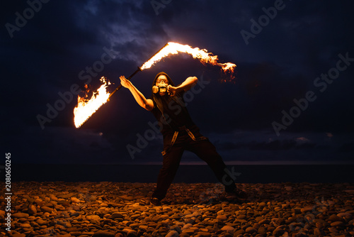 Fire performer with burning torches at night