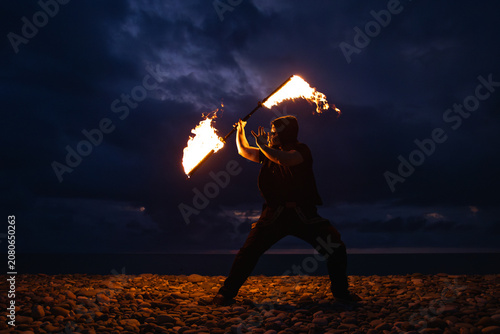Fire performer with burning torches at night