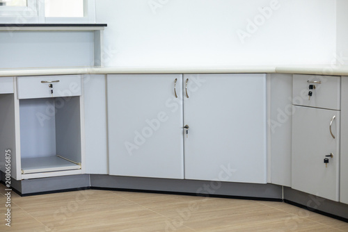 Modern white kitchen cabinet corner countertop metal handle lockable storage clean minimalist design empty drawer tiled floor bright interior functional workspace