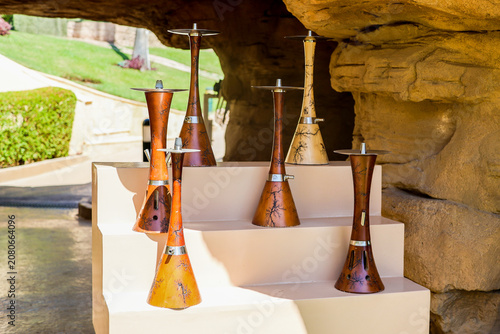 Assortment of hookahs neatly arranged on a shelf in a cozy summer cafe with relaxed ambiance.