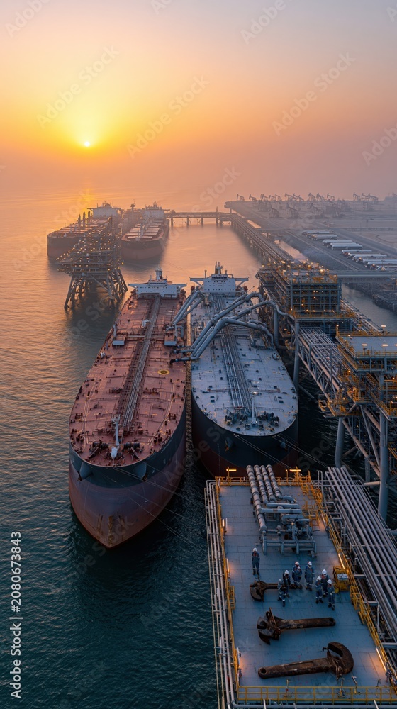 Fototapeta premium Aerial View of Large Tanker Ships Docked at an Industrial Port During a Misty Sunrise