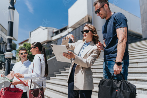 Photography Business associates discuss documents and plans on a tablet while standing on outdoor steps
