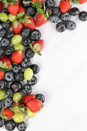 Fresh ripe Blueberry strawberry grape macro closeup on wood dark white background
