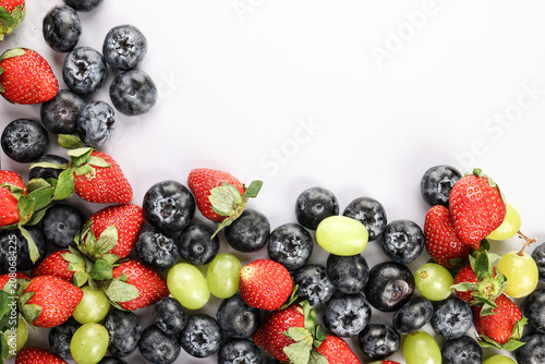 Fresh ripe Blueberry strawberry grape macro closeup on wood dark white background
