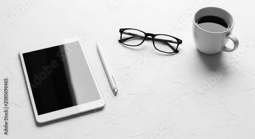Minimalist monochrome flatlay of a modern workspace with tablet, stylus, glasses, and coffee mug