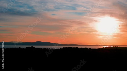 Vibrant orange sunrise over ocean bay with mountain silhouette copy space