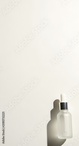 Frosted glass dropper bottle with elegant shadow on light background