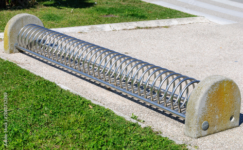 Modern stainless steel bicycle rack in a public park, promoting sustainable urban mobility with clean design, outdoor infrastructure, and ample copy space.