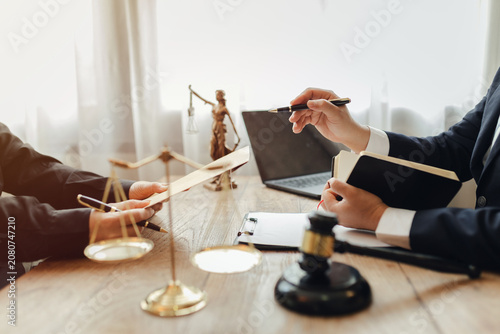 The lawyer sat in front of a laptop in a room filled with documents and smartphones, with a hammer and scales beside him, advising his female client on matters of justice and legal principles.