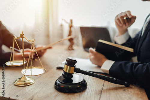 The lawyer sat in front of a laptop in a room filled with documents and smartphones, with a hammer and scales beside him, advising his female client on matters of justice and legal principles.